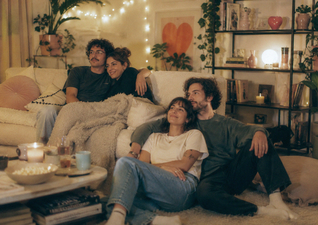 Polycule enjoying each other's company on a couch, surrounded by a warm and inviting living room atmosphere.