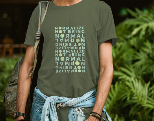 A man wearing a green shirt featuring the slogan "NORMALIZE NOT BEING NORMAL" in a fun, eye-catching style.