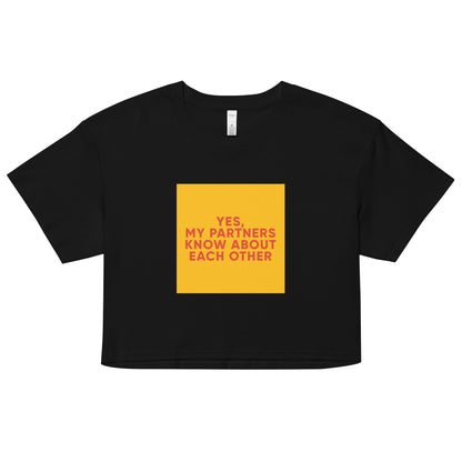 Black cropped tee with bold orange-red text reading “Yes, My Partners Know About Each Other,” cheeky ENM-affirming statement top for open-relationship style.
