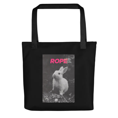 Black cotton tote bag with bold pink “ROPE” text and grayscale bunny illustration – playful, minimalist nod to alternative expression and rope art.