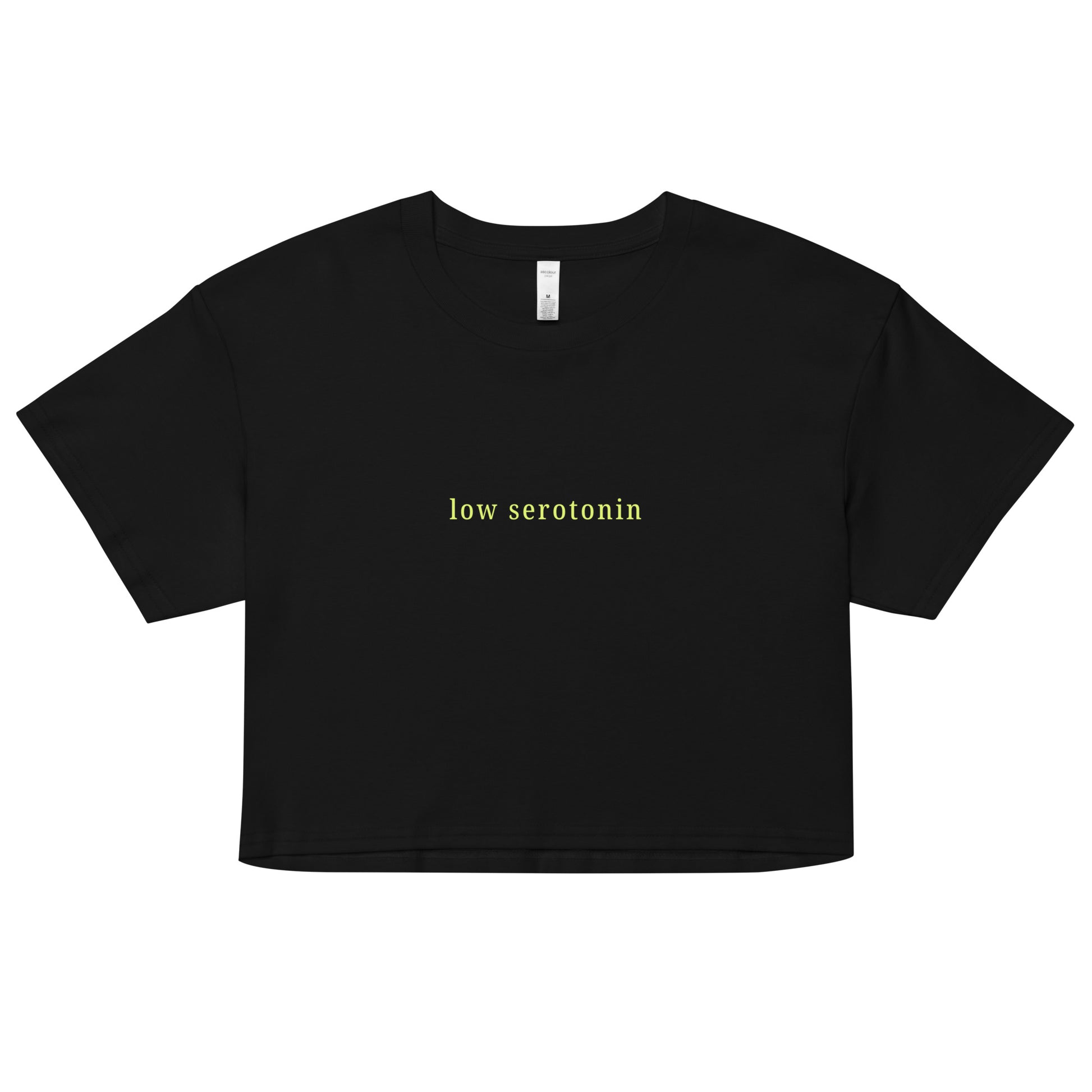 Black crop top with light yellow-green text reading “low serotonin” – sarcastic neurodivergent cropped tee for everyday style.