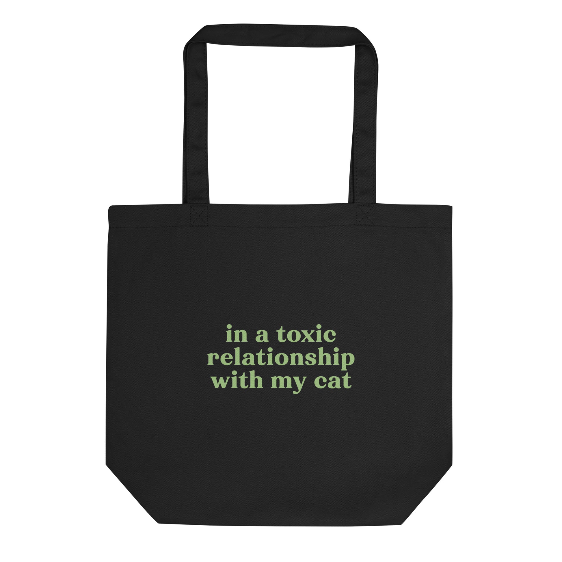 Black eco tote bag with green text saying 'In a Toxic Relationship with My Cat' for cat lovers tired of dating.