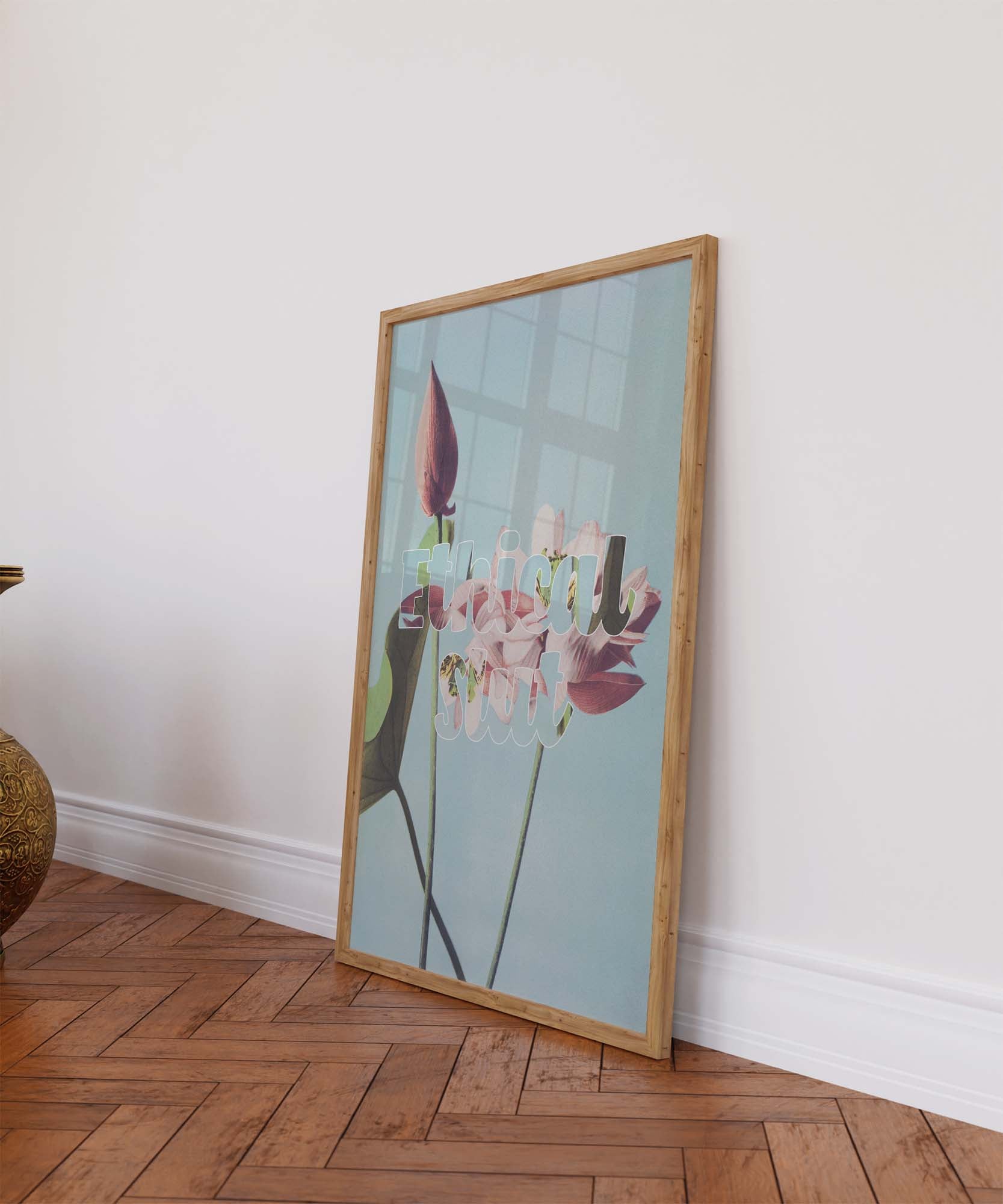 Framed vibrant sex-positive poster with "Ethical slt" printed on vintage illustration leans against a colorful wall on a wooden floor.