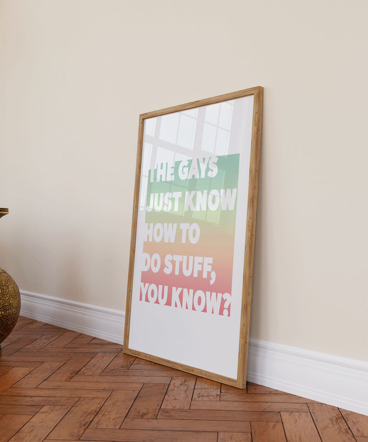 Framed queer printable wall decor with colorful background leans against a colorful wall on a wooden floor.