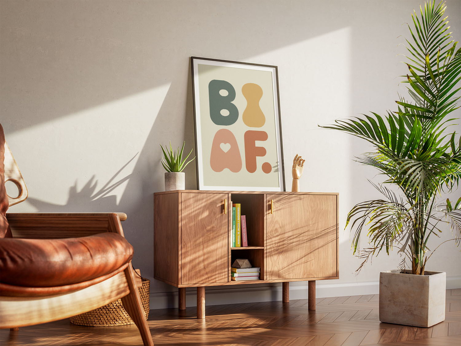 A modern living room with a wooden sideboard, leather chair, green houseplant, and a framed wall art print with the words 'BI AF' in bold colors.